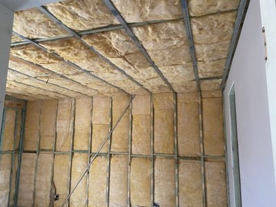 Bulk batts pressed snug into timber stud wall framing on a new build