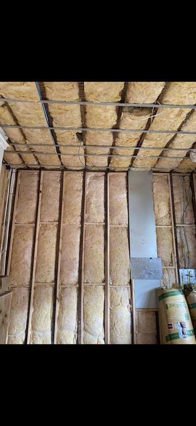 Old water-damaged batts being pulled from a ceiling cavity and bagged on site